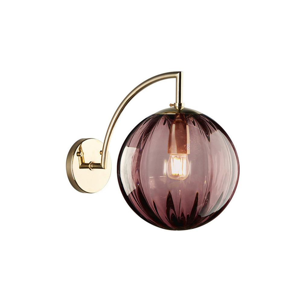 Isolated rose-red ribbed glass globe on gold-tone arched arm and round wall plate against white