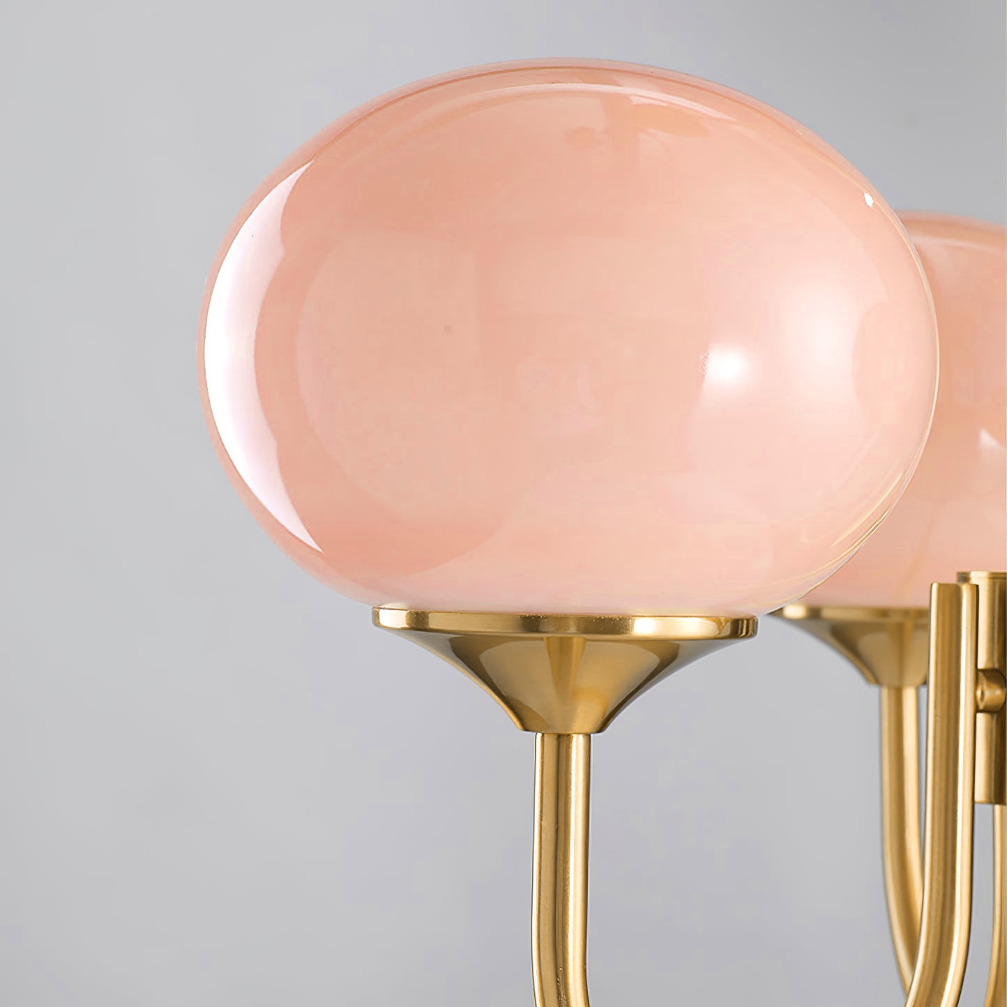Pink glass globe resting on a flared gold-tone metal cup, shown in close detail