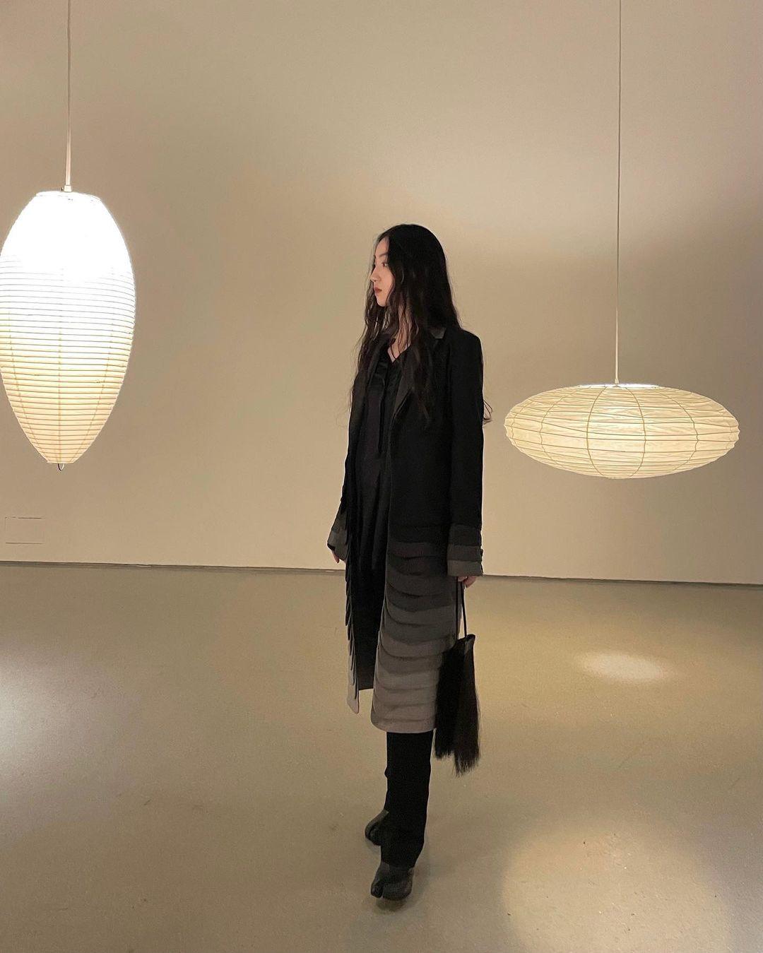 Flattened and tall oval paper pendants with a visitor between them in an exhibition room