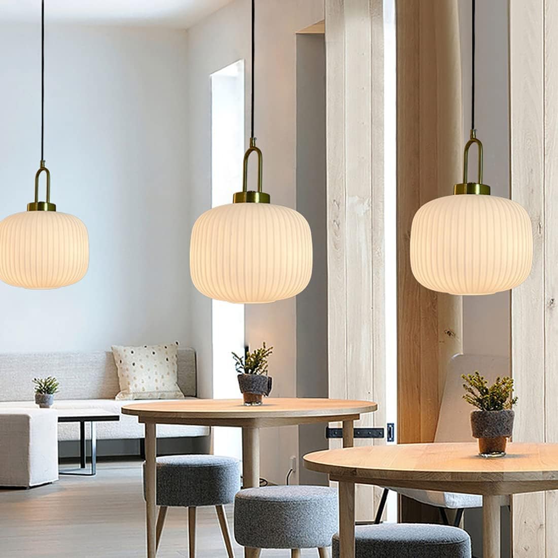 White ribbed glass pendants with gold-tone loops above round tables and upholstered seats
