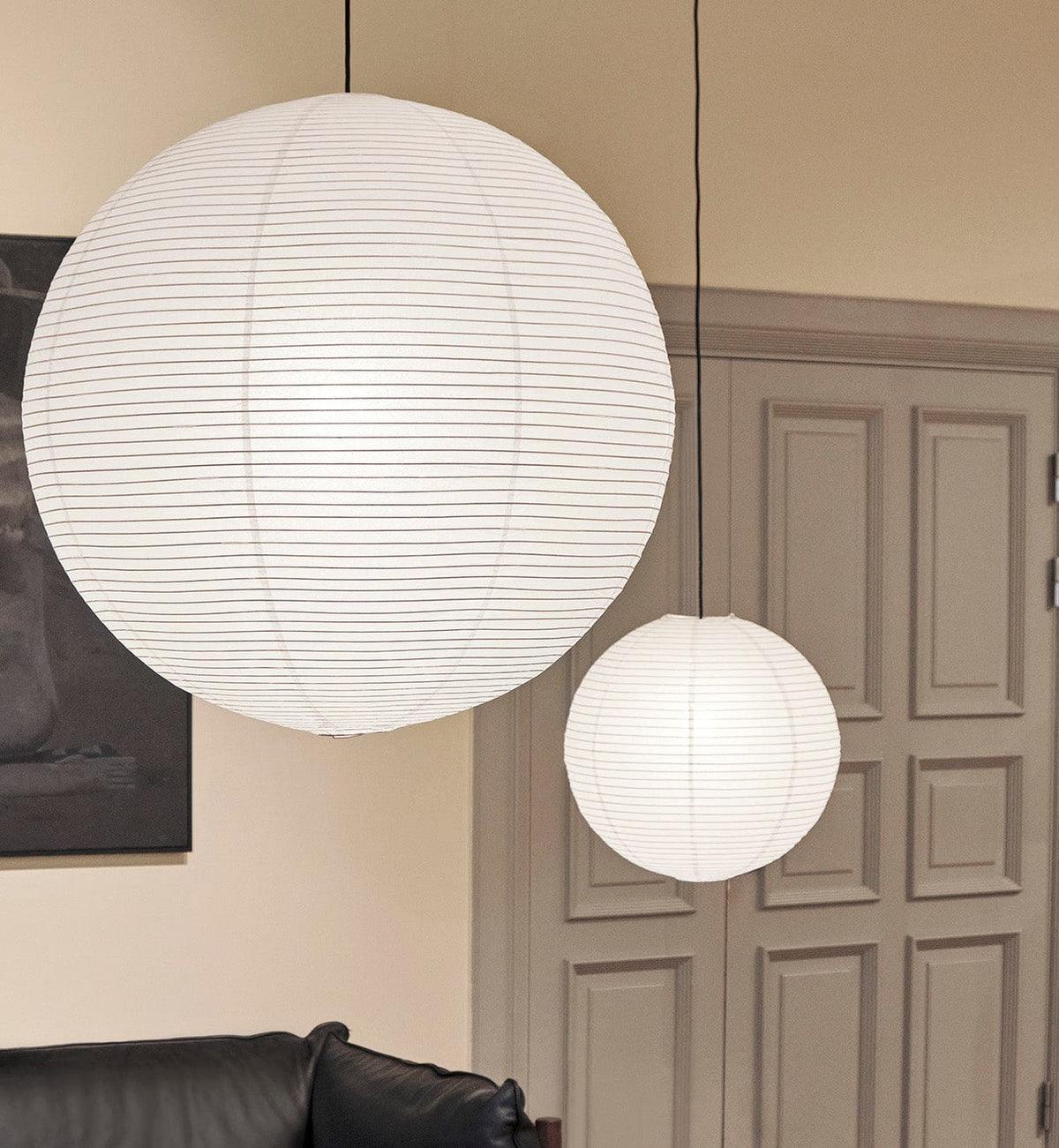 Two White globes above a black leather sofa beside a paneled door and framed artwork