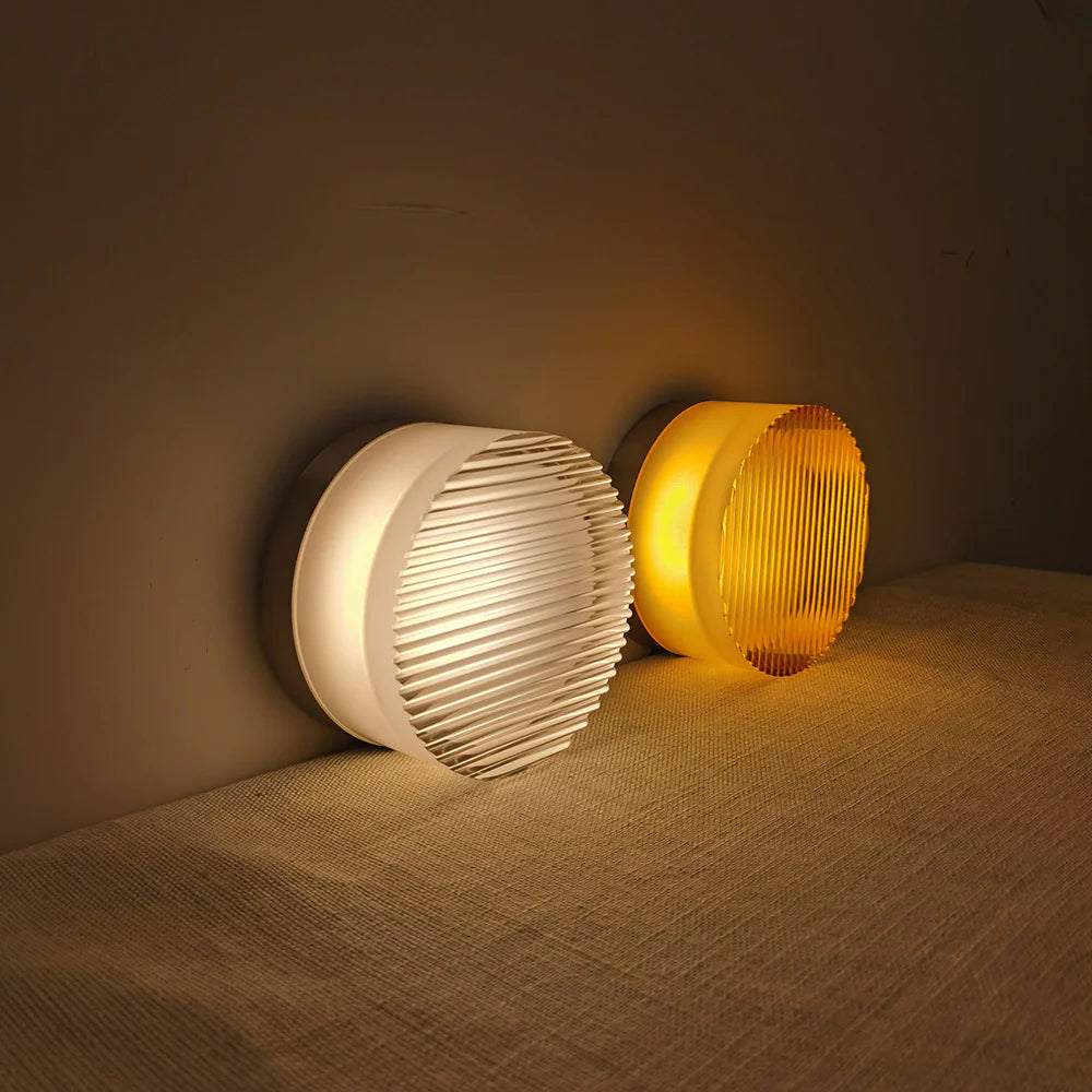 White and amber round ribbed fixtures resting against a wall on an upholstered bench