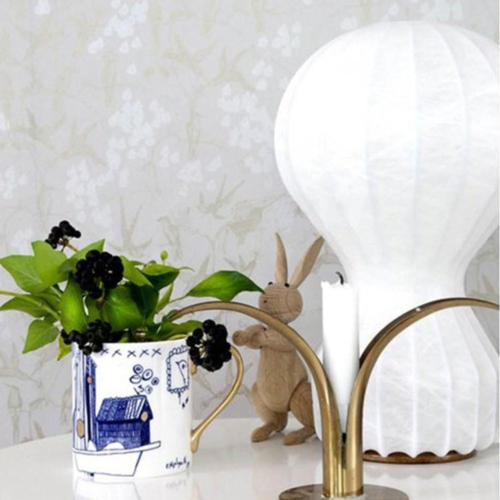 Close view of the white lamp’s textured ribs and scalloped lower edge near a patterned foliage vase and wooden rabbit ornament