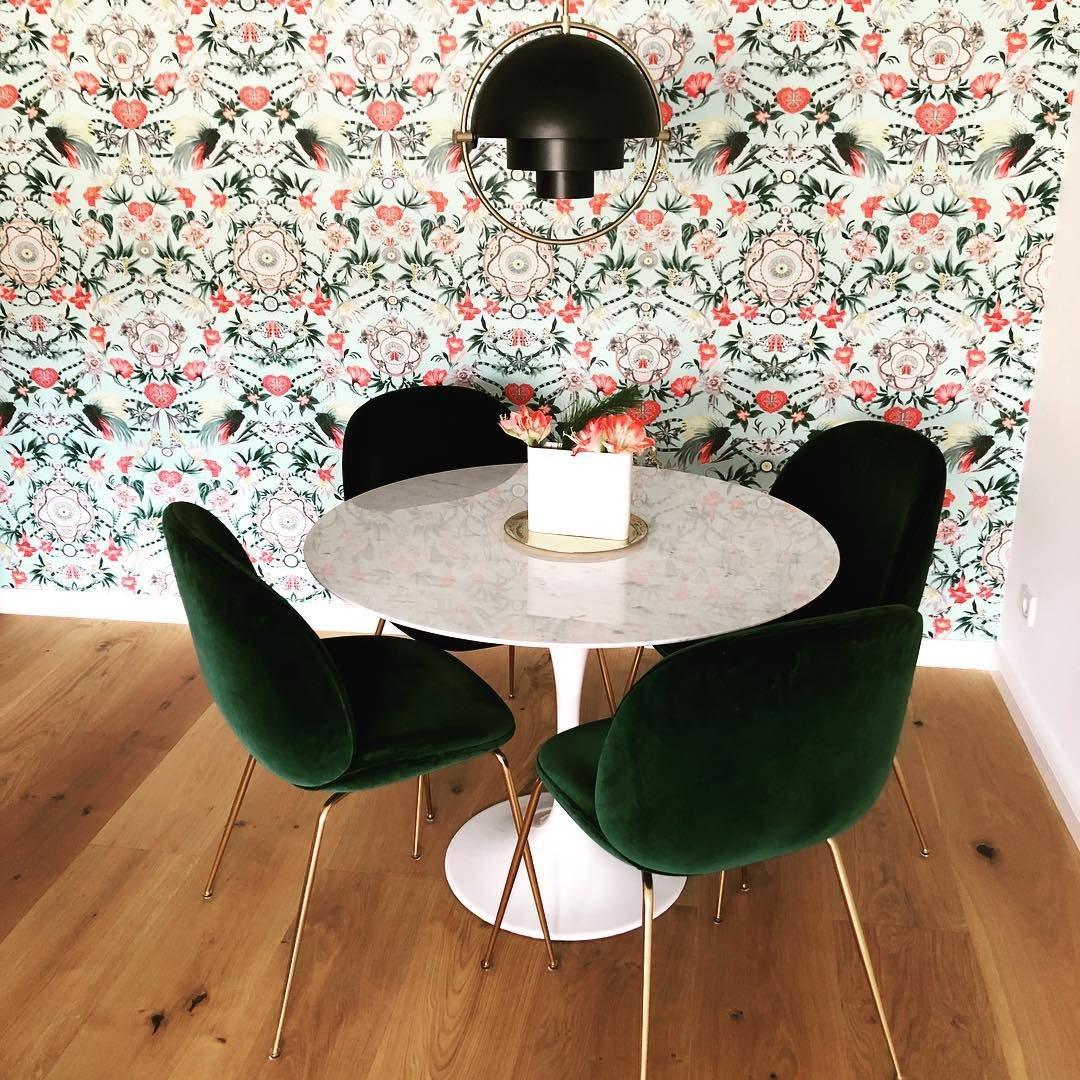 Black ring pendant over a marble table in a room with floral wallpaper.