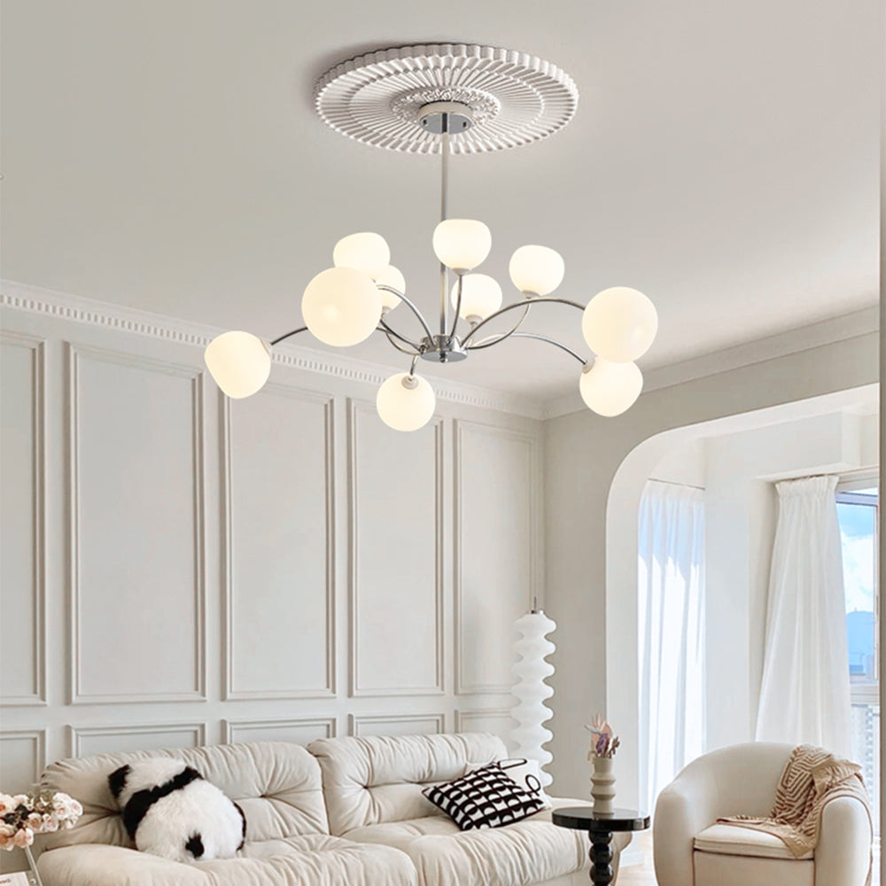 Chrome white-globe chandelier above a white sofa near a window and a separate wavy floor lamp