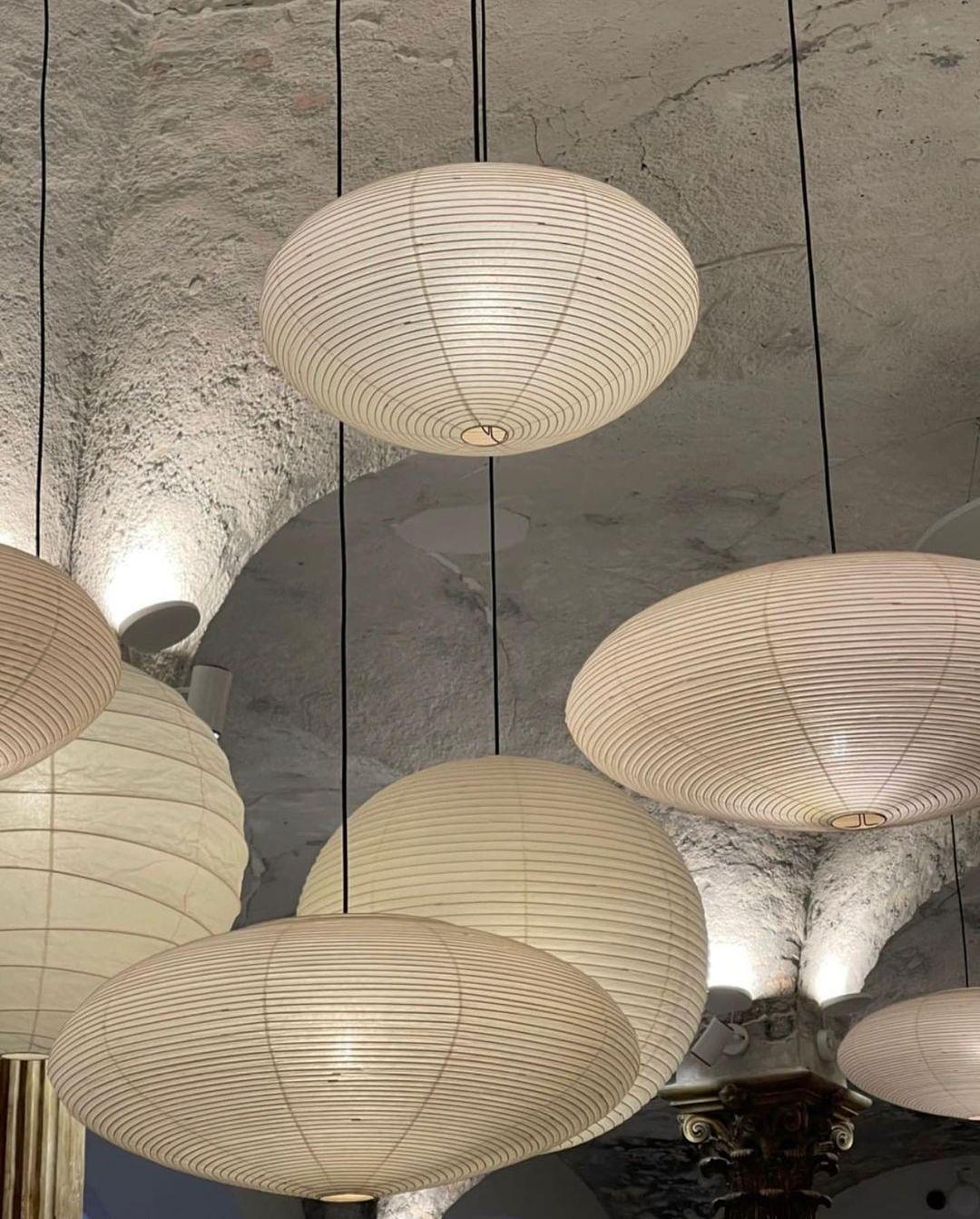 Flattened and globe paper shades on dark cords beneath a vaulted stone ceiling