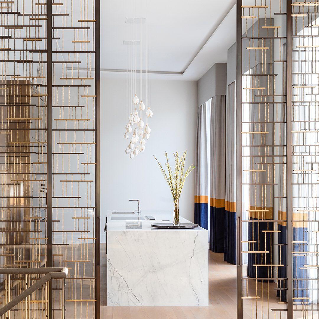 White flower-bud cluster above a kitchen island beyond a gold geometric divider