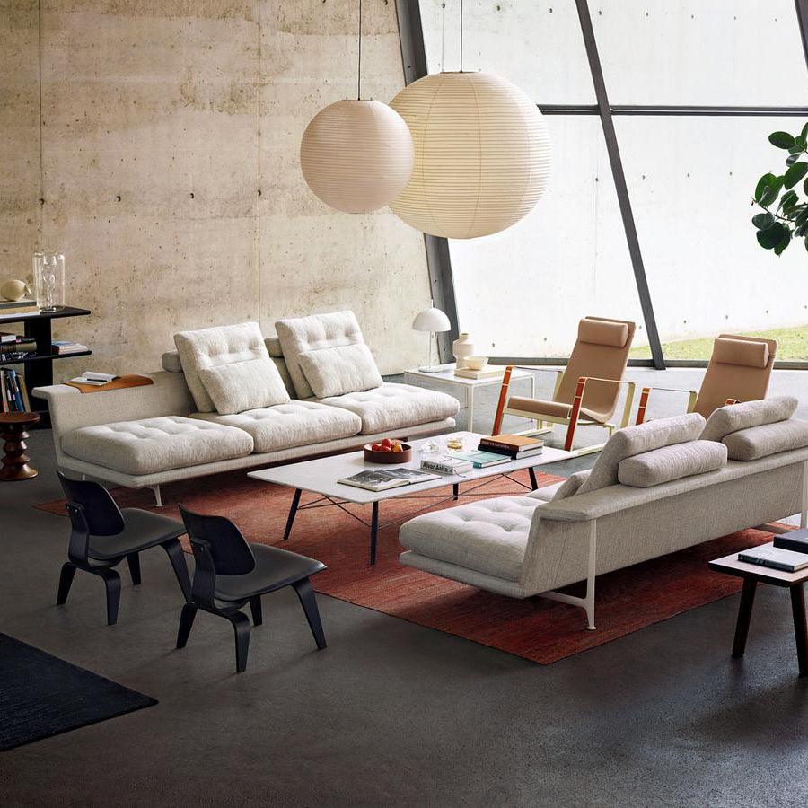 Two White globes above grey sofas and a white coffee table with wood chairs and a red rug