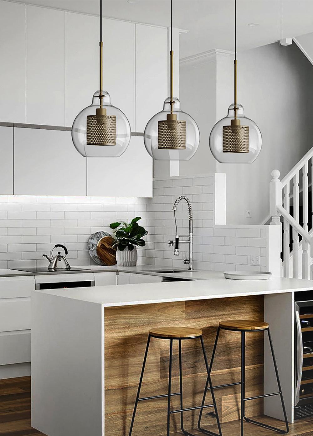 Clear glass pendants along a white kitchen island