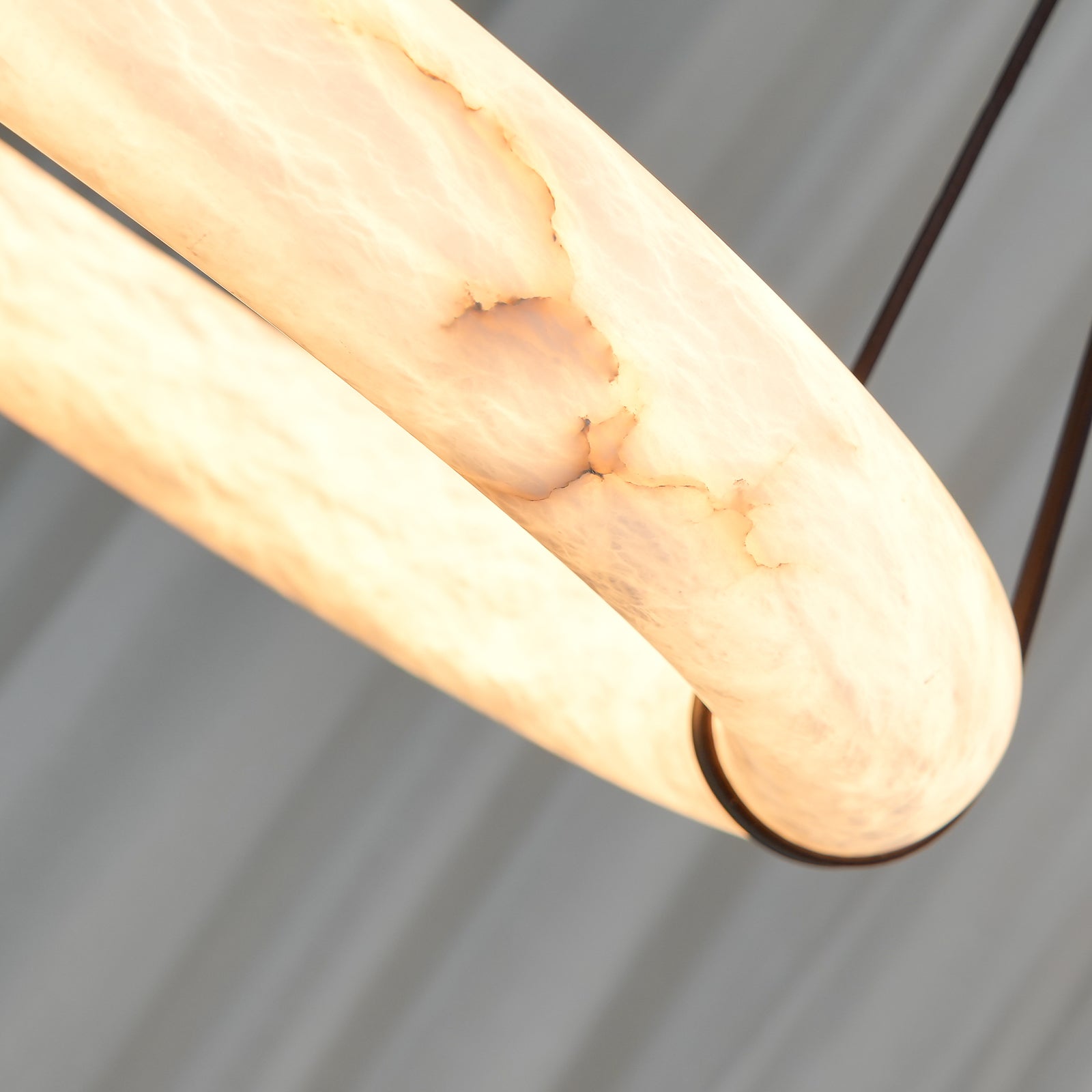 Underside detail of a glowing alabaster ring with a curved strap below it.