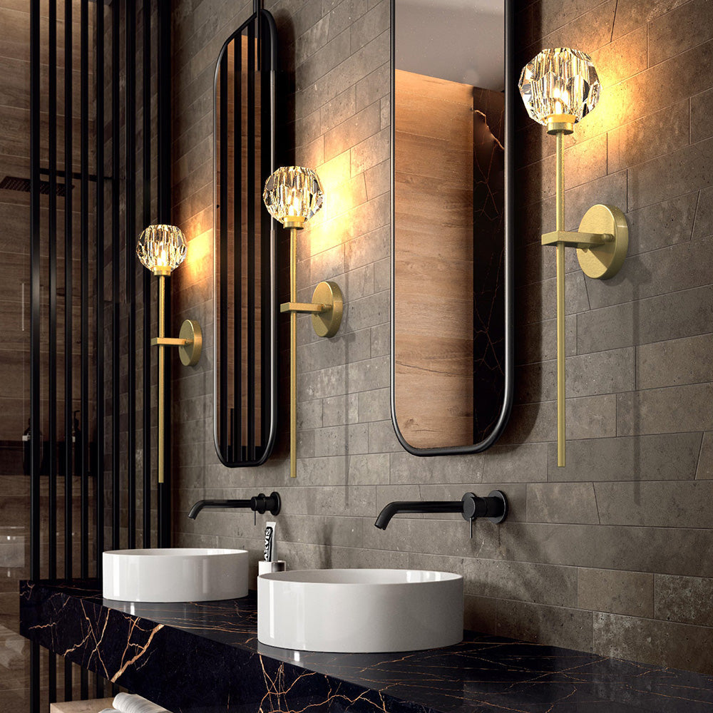 Three separate faceted ball wall lights beside tall black-framed mirrors above white basins and dark countertop