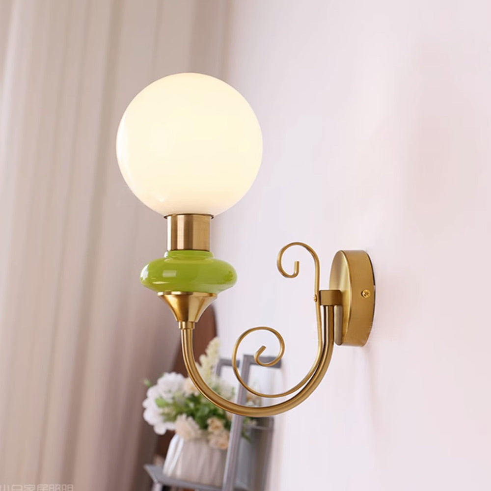 Gold-and-green globe wall light beside a curtain