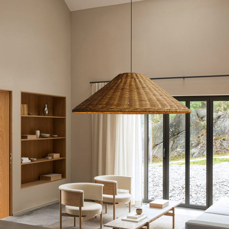 Brown rattan cone pendant above pale seating and a low table beside wooden shelves and glass doors
