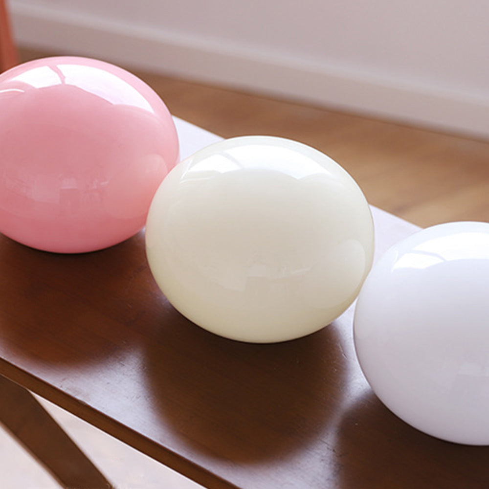 Pink, beige and white loose rounded glass shades displayed together on a wooden table