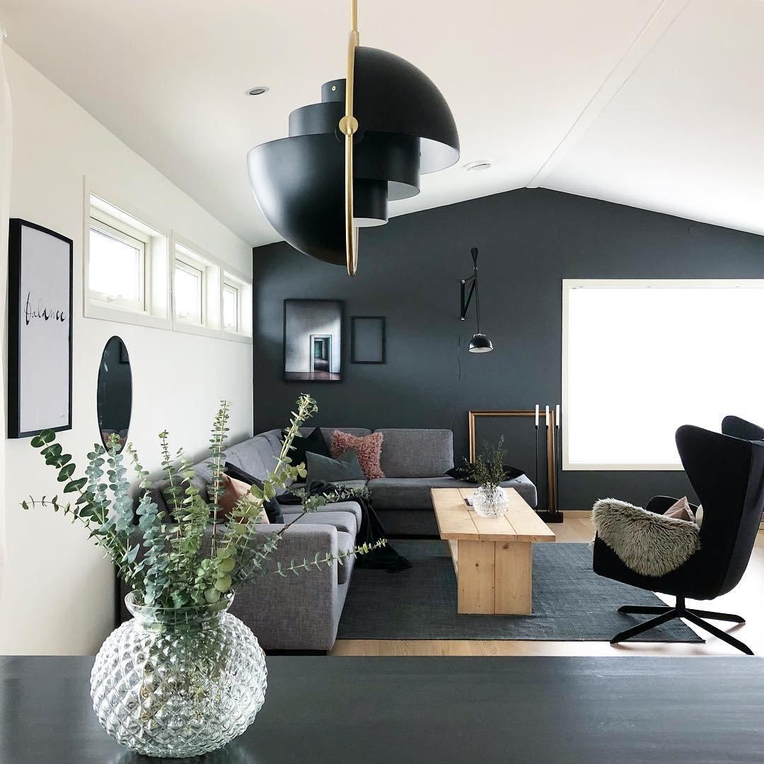 Black shade halves in opposing positions over a desk in a living room.