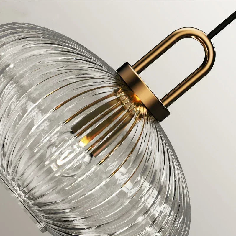 Angled close-up of clear glass ribs, a gold-tone loop and collar, and black cord