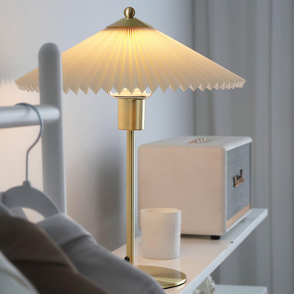 Close view of white pleated shade and gold-tone stem beside a pale radio and cup