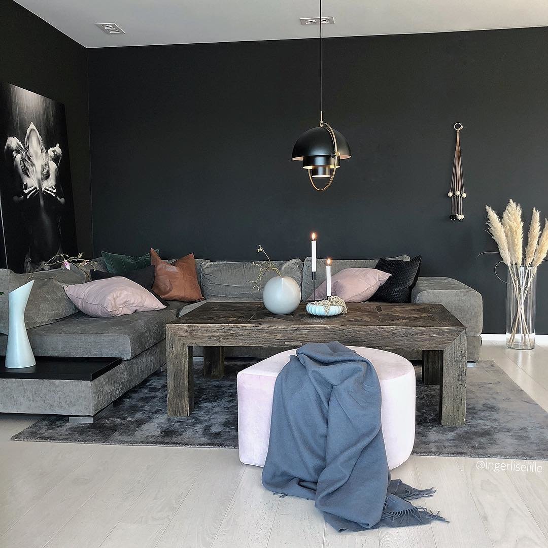 Black-and-gold ring pendant over a dark sofa in a furnished living room.