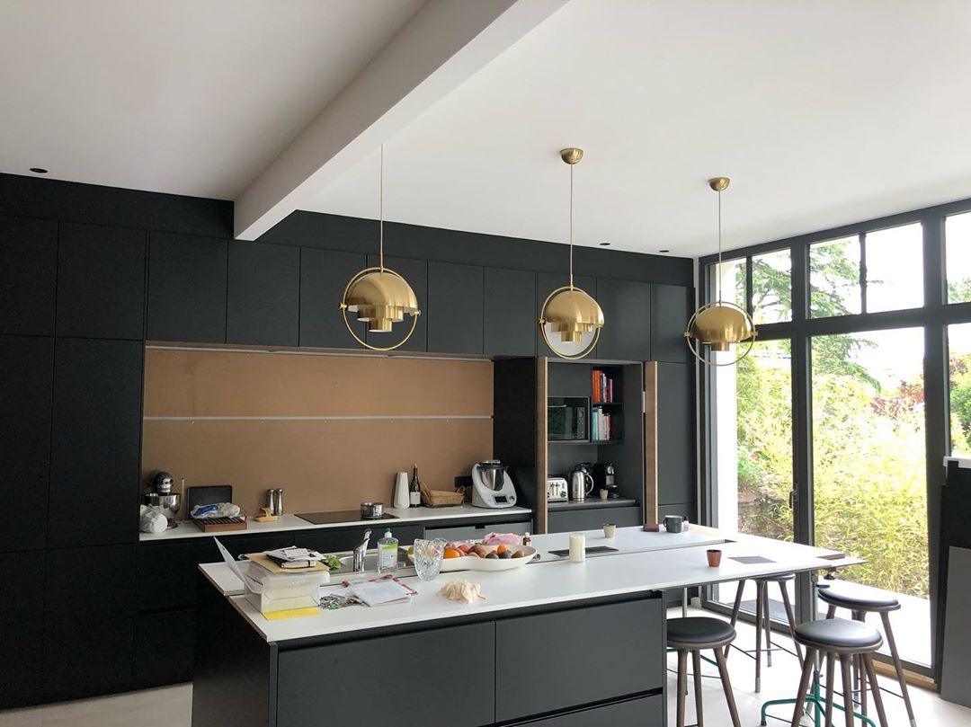 Gold-toned ring pendants over a kitchen island facing garden windows.