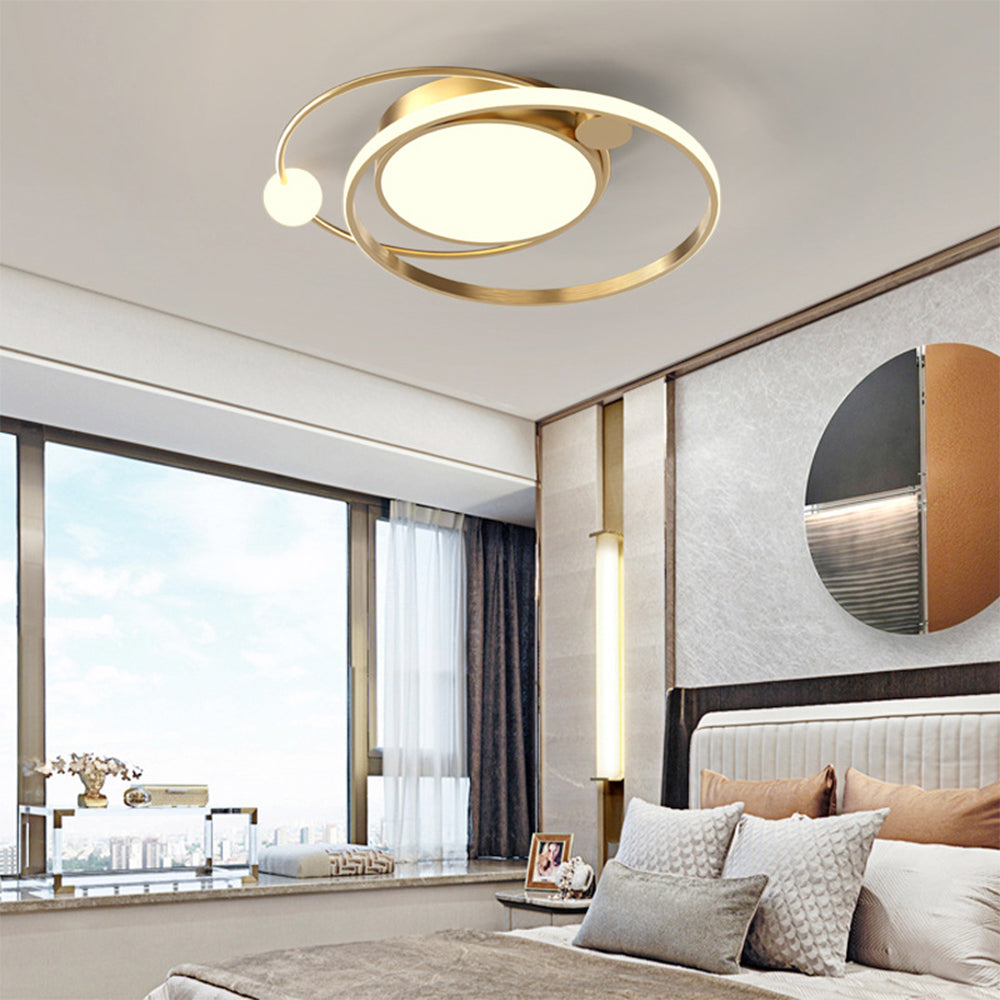 Gold-tone orbital ceiling fixture above a bedroom with a large window, circular wall art and pillows
