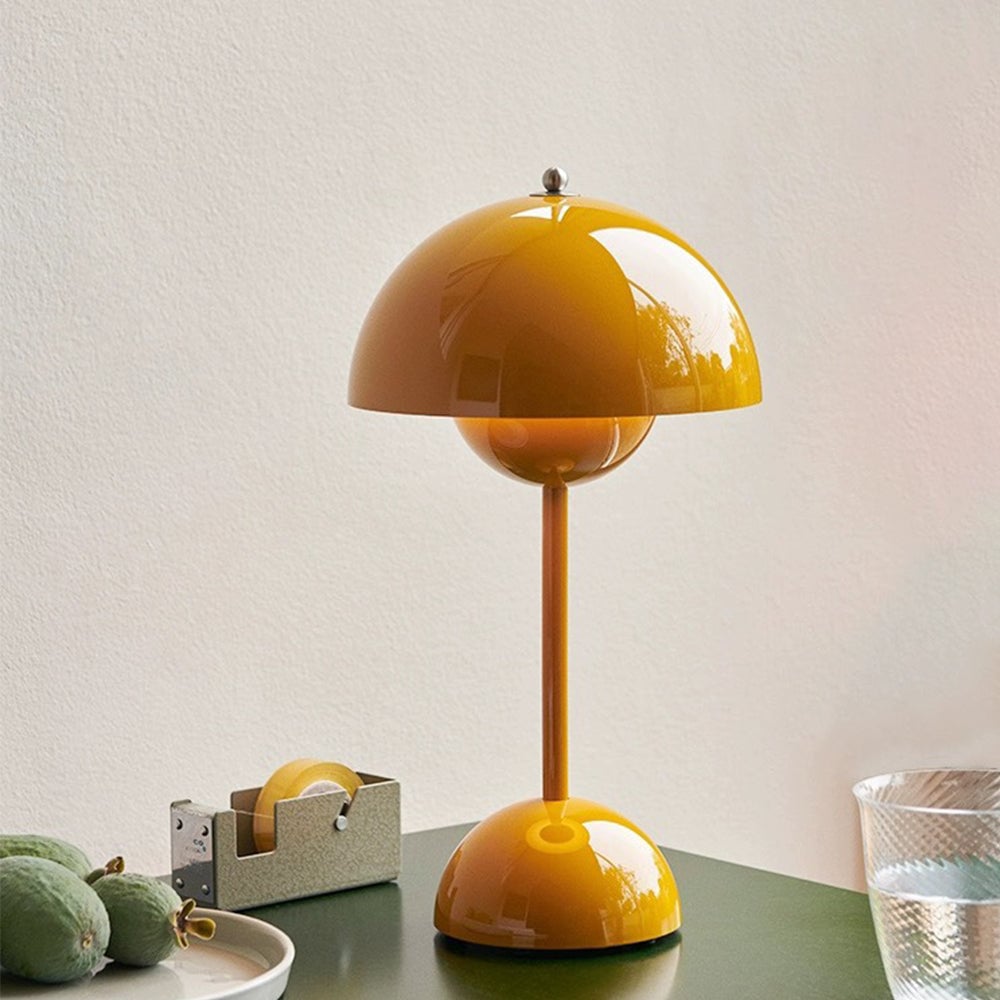 Yellow dome lamp on a green table beside a tape dispenser, fruit plate and glass