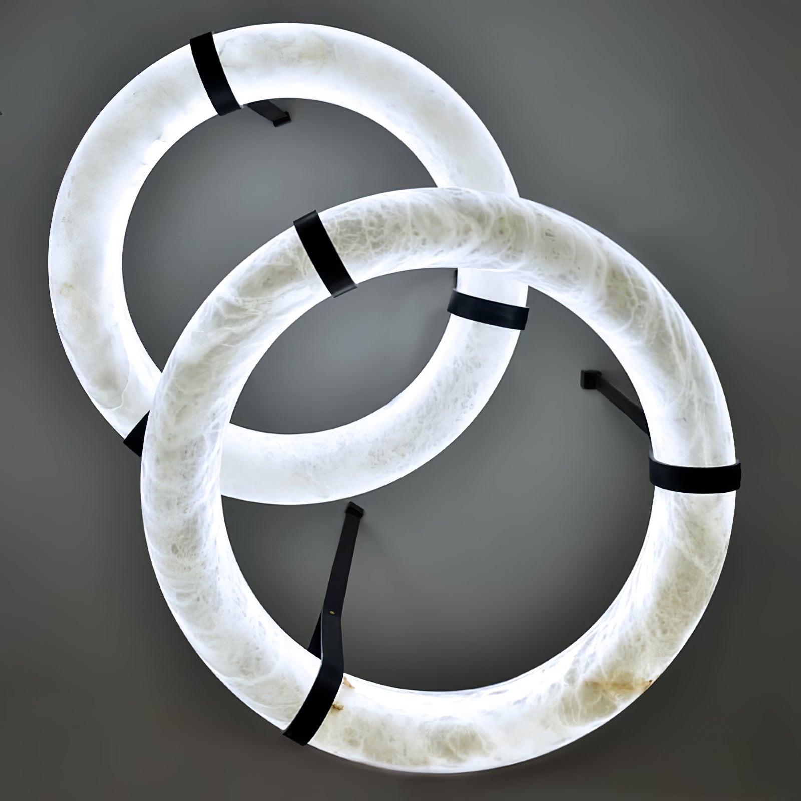 Three illuminated alabaster rings overlapping in a close view with dark straps.