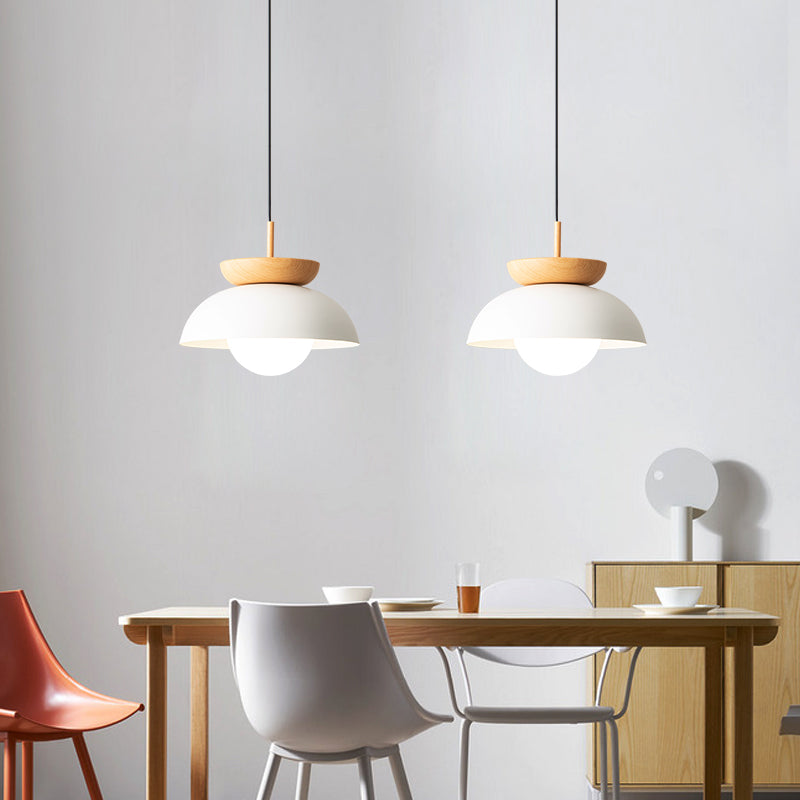 Two White metal dome pendants with wood accents above a dining table and modern chairs
