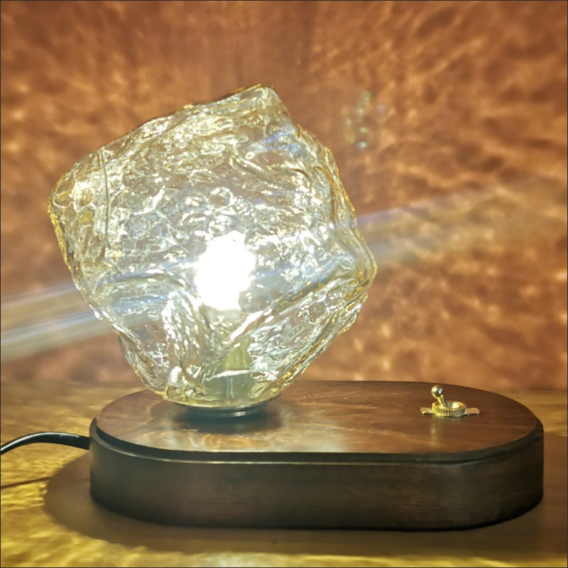 Second close view of grey Ice Stone glass with bright photographed light above an oval wood base