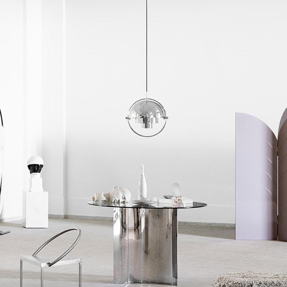 Chrome ring pendant over a reflective round table in a pale interior.