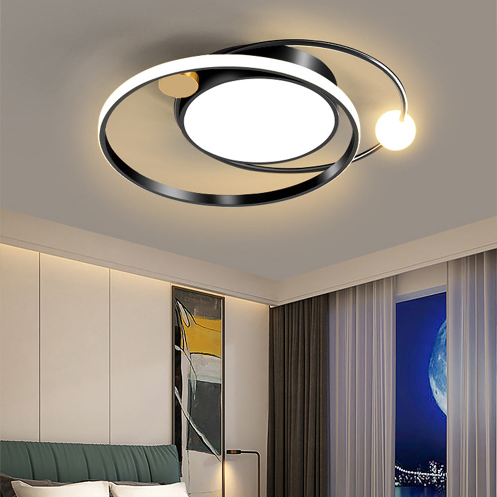 Black orbital ceiling fixture above a bedroom with green headboard and abstract wall art