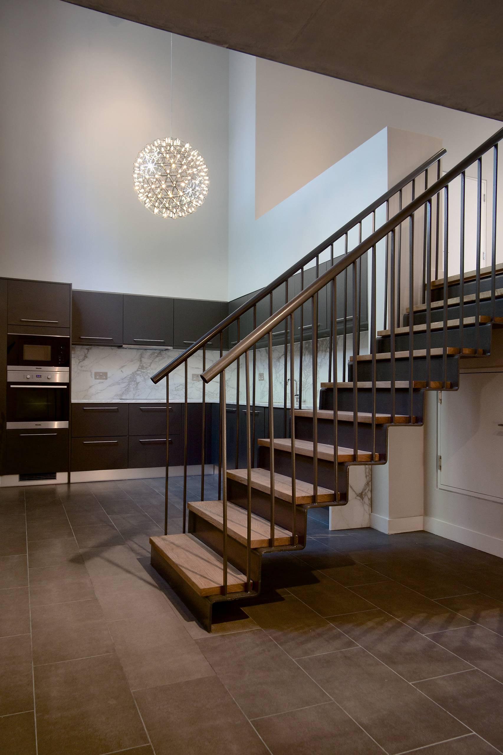 Single lattice globe high above dark kitchen cabinets beside wooden stairs