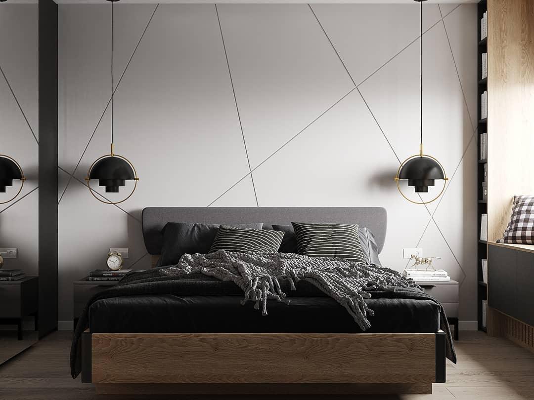 Two black adjustable pendants on long cables beside a bed.