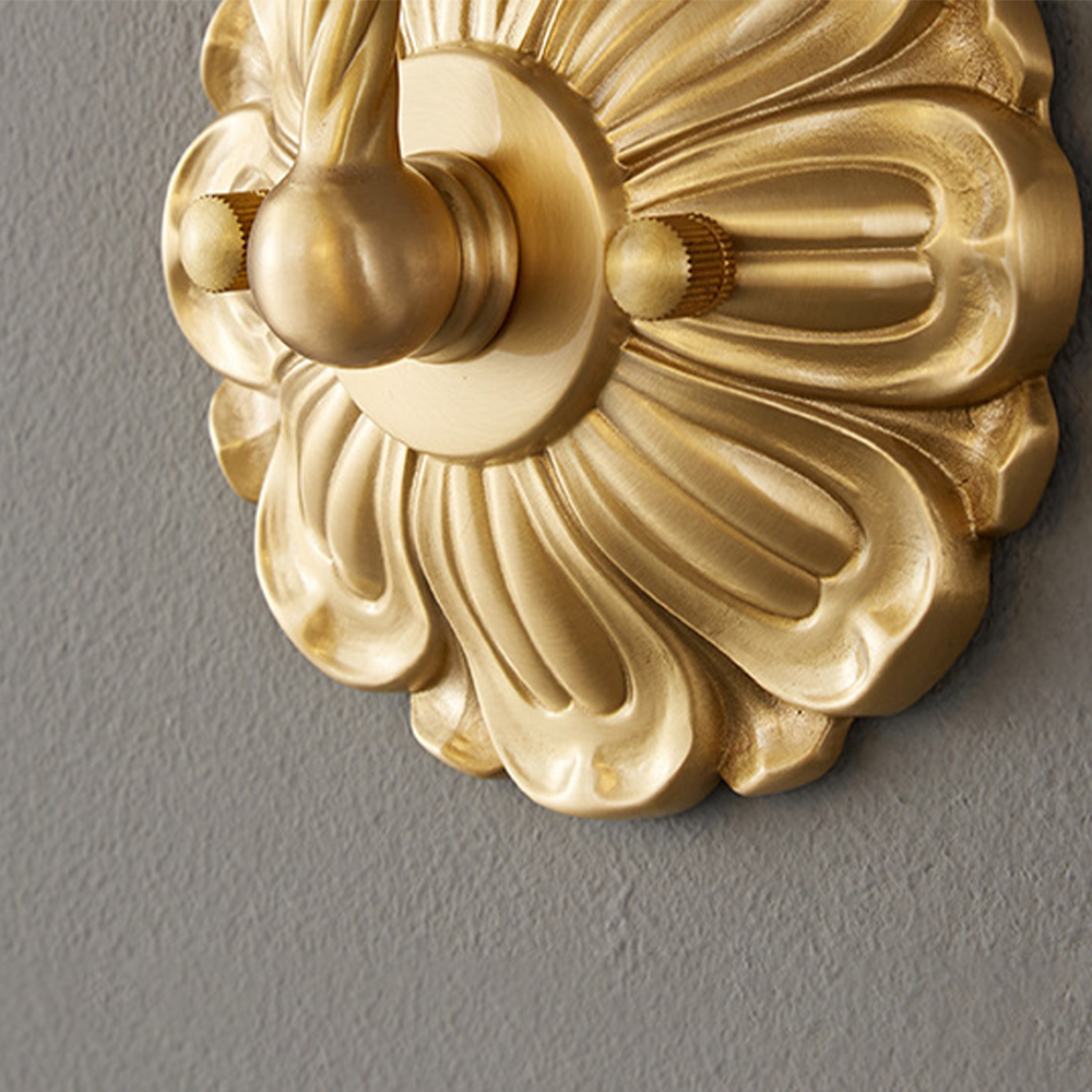 Close view of gold-tone fluted floral wallplate with rope-textured arm root and two knurled fixing knobs