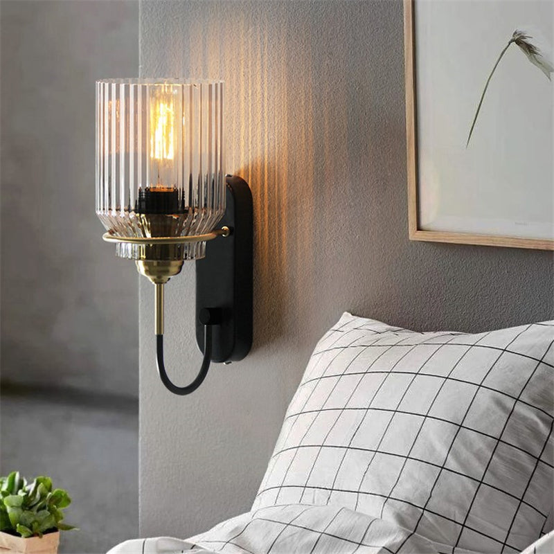Industria fixture pictured with the ribbed glass shade facing upward beside a checked pillow and botanical picture