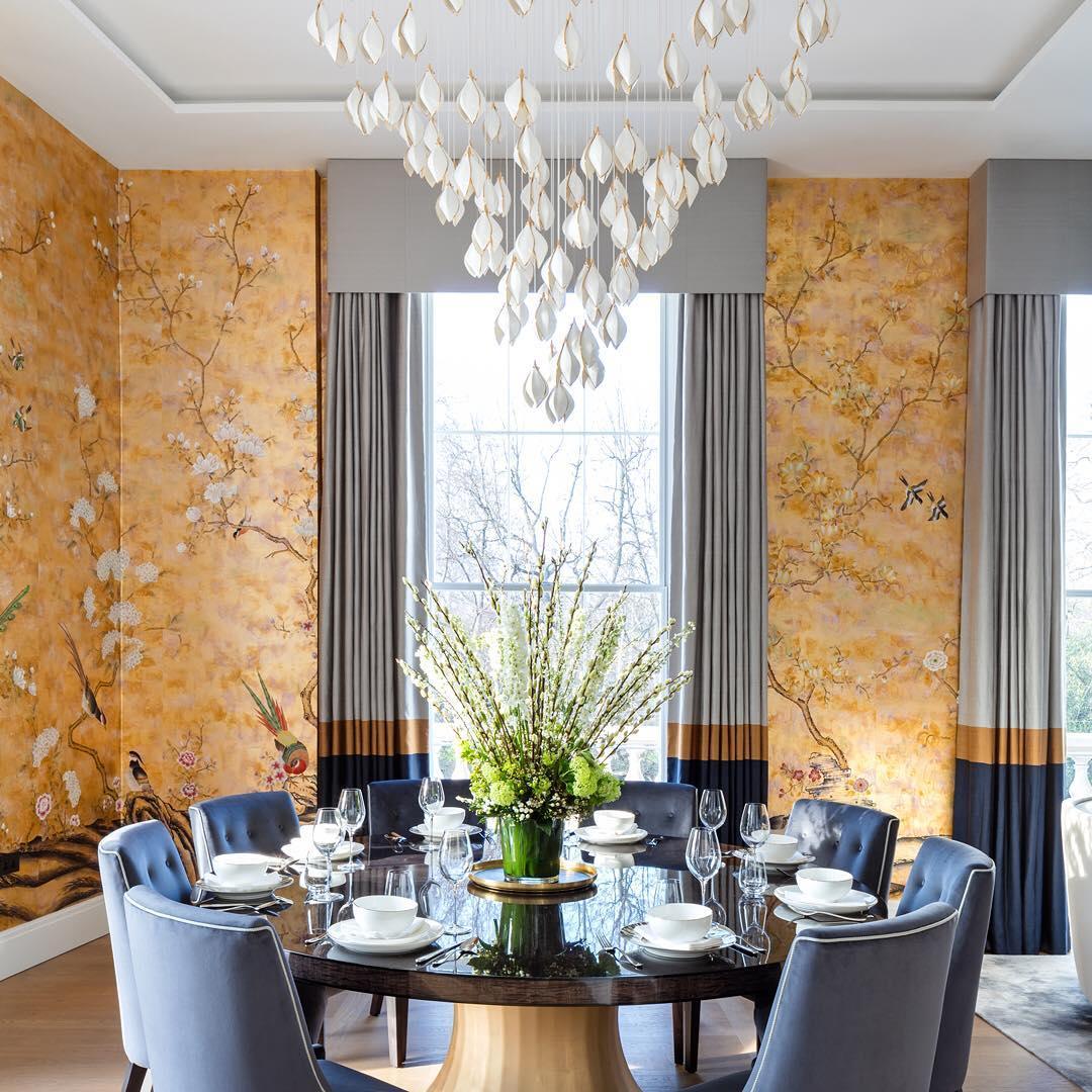 White petal cascade above a round dining table, blue chairs and flower vase