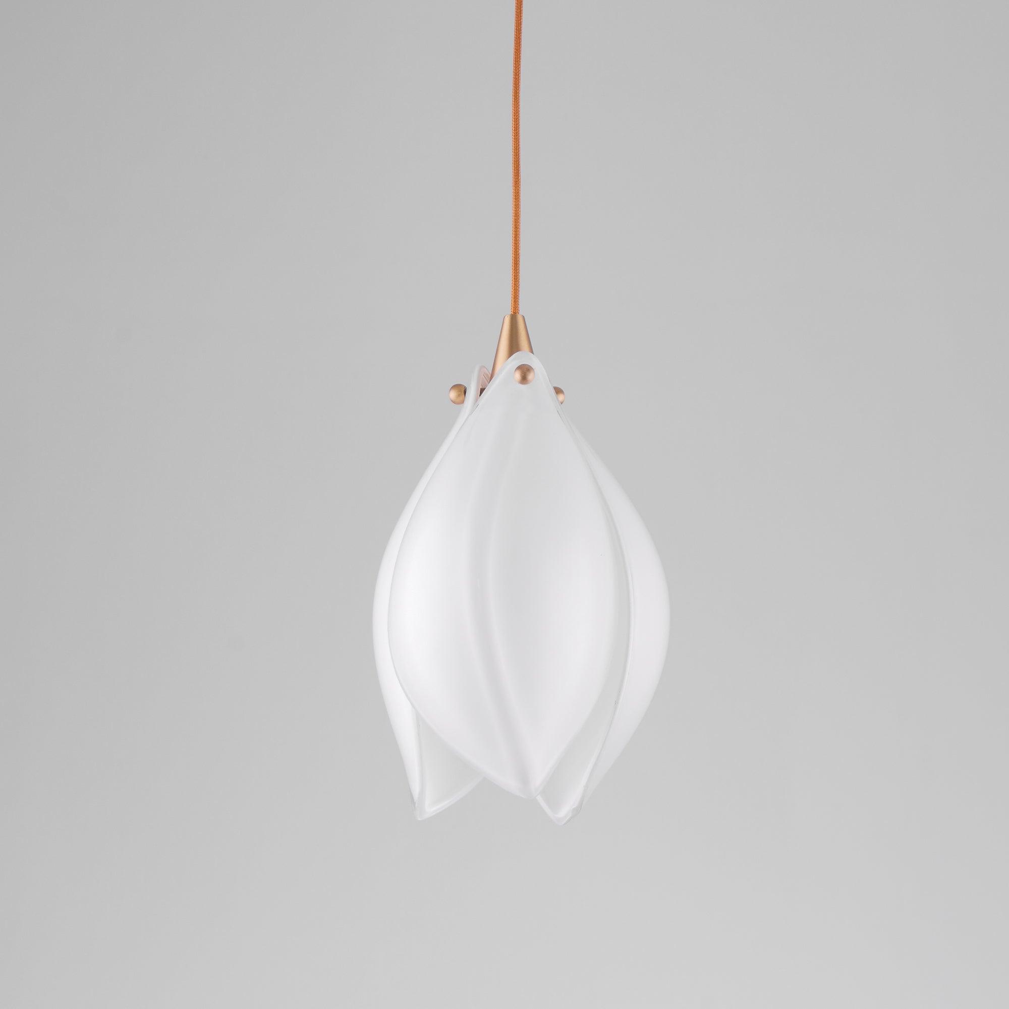 Single unlit white petal bud with gold-tone top and orange-brown cord against grey