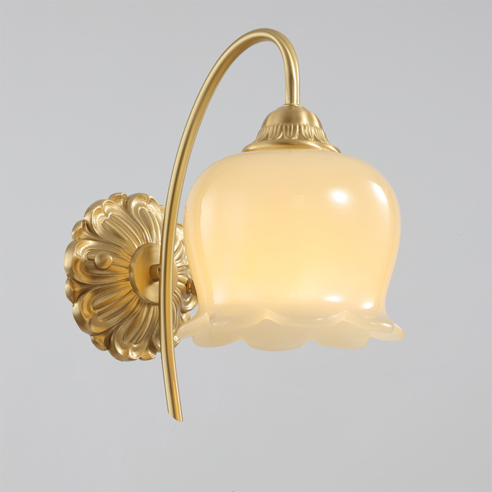 Close view of lit scalloped glass shade, ribbed top cap, curved arm and ornate floral wallplate