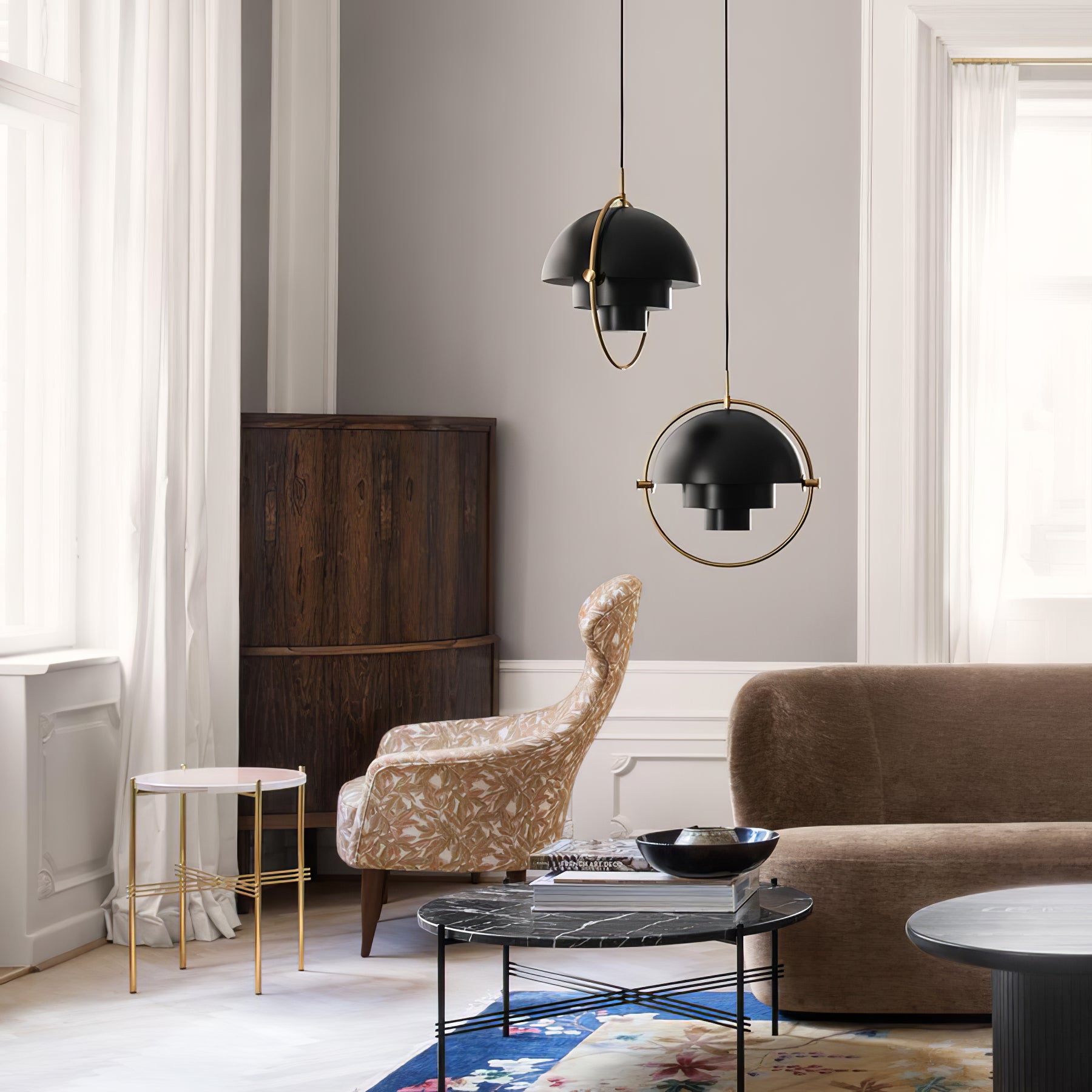 Two black sculptural pendants hanging beside a sofa and spotted chair.
