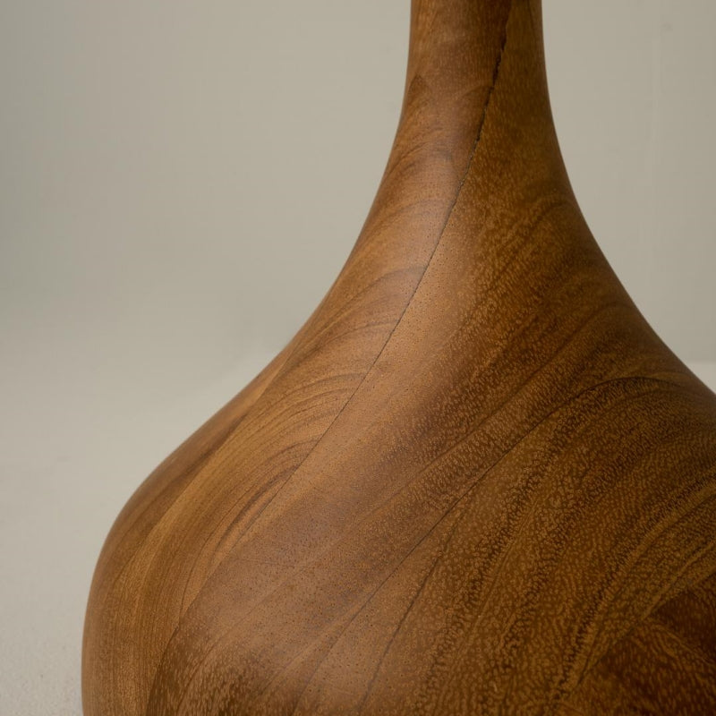 Close-up of the wood-grain pattern on the rounded lamp base where it narrows into the stem