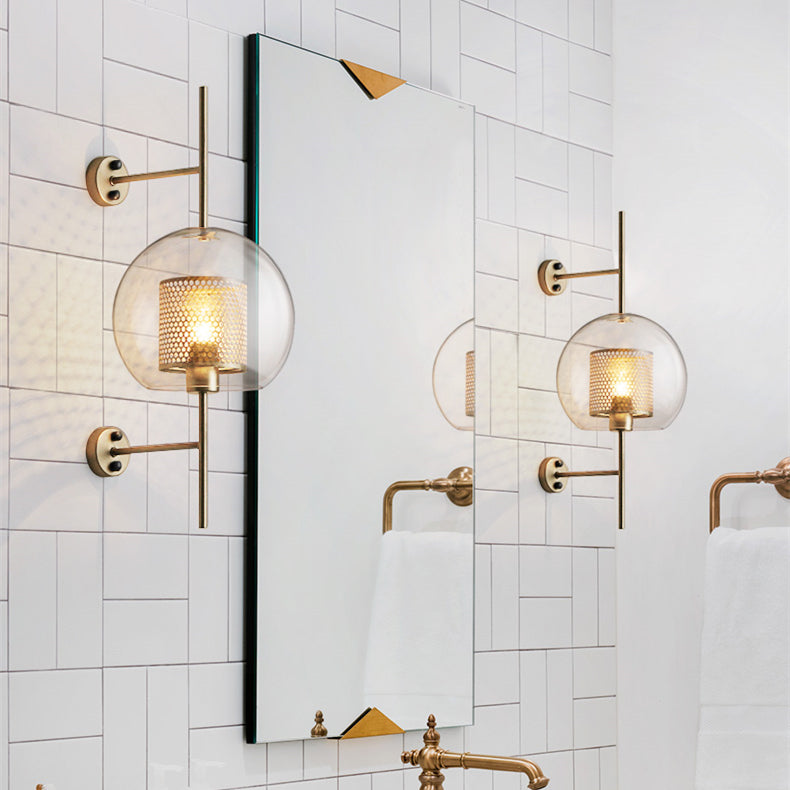 Globe glass sconce beside bathroom mirror with gold-tone tap and towel fittings, showing additional mirror view