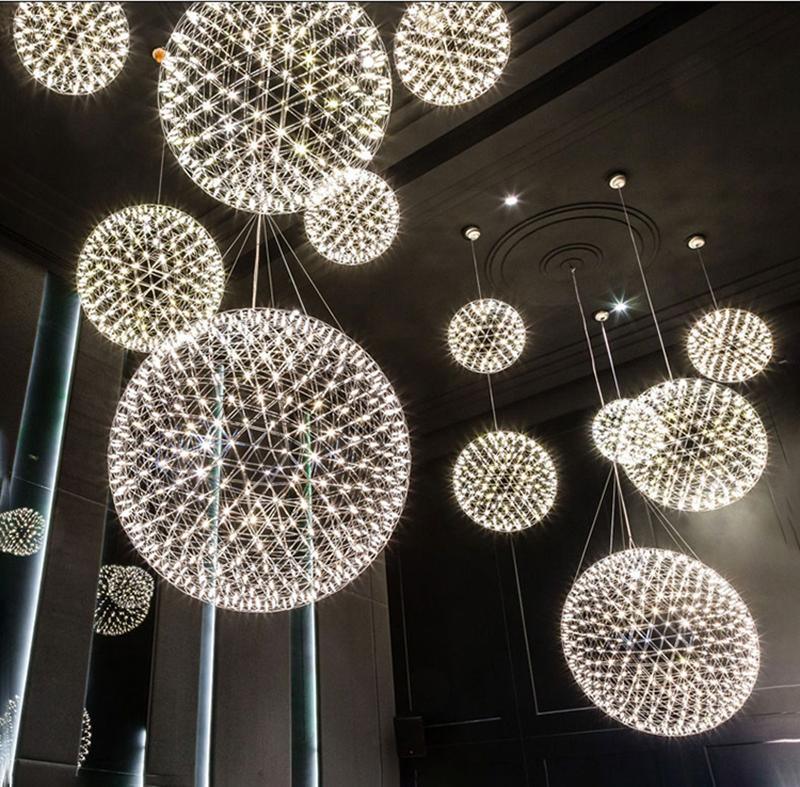 Multiple illuminated lattice globes suspended at different heights in a tall dark interior