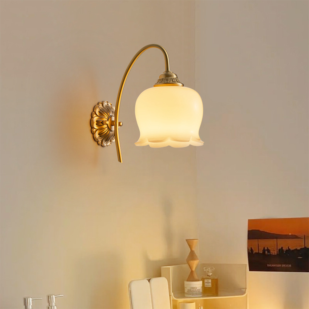 Lit glass wall sconce above counter with jars, bottle, hourglass sculpture and orange artwork
