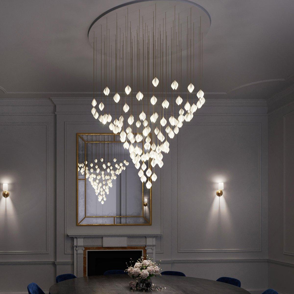 Large flower-bud cascade over a dark round table and blue chairs before a gold mirror