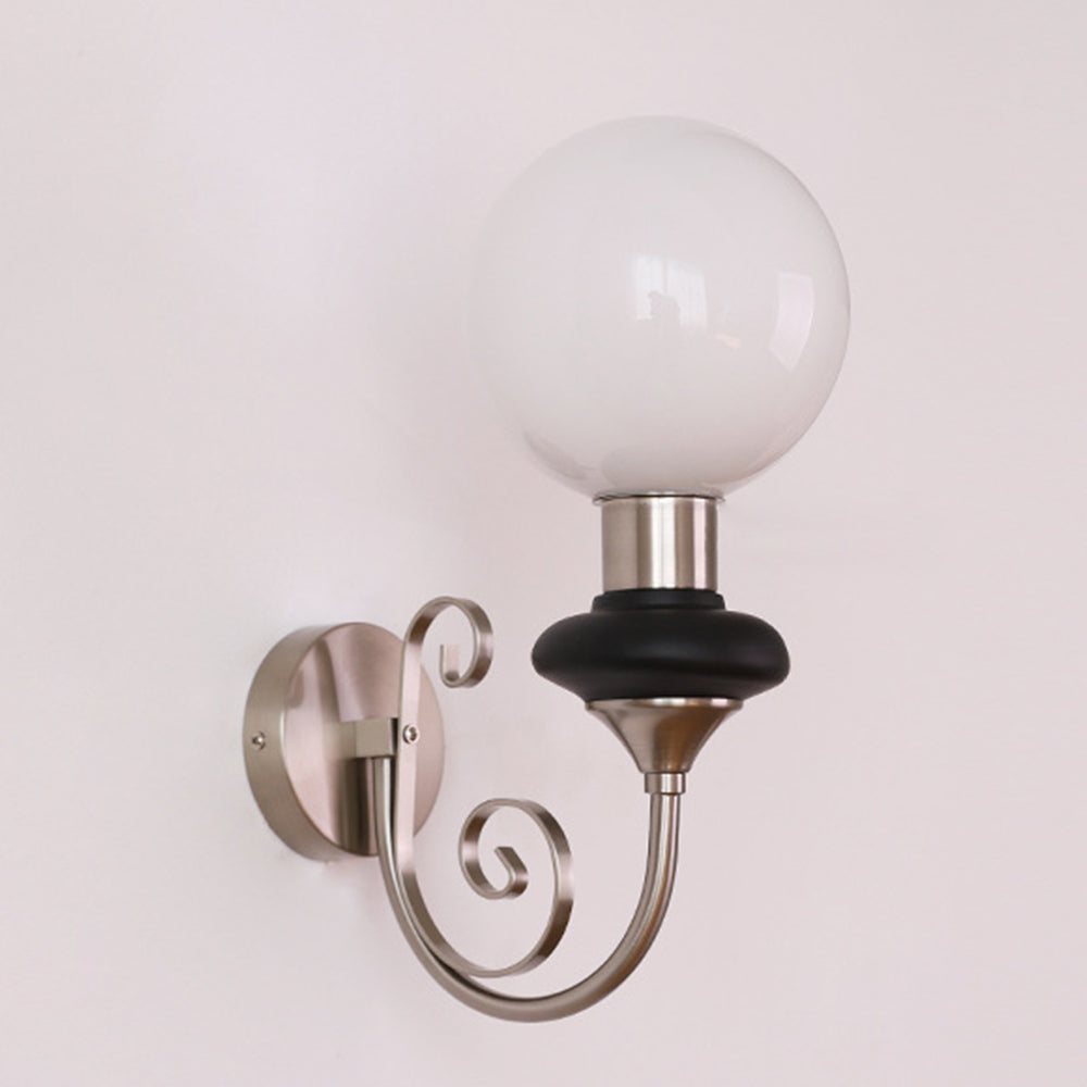 Unlit white globe on chrome-and-black scroll-arm sconce