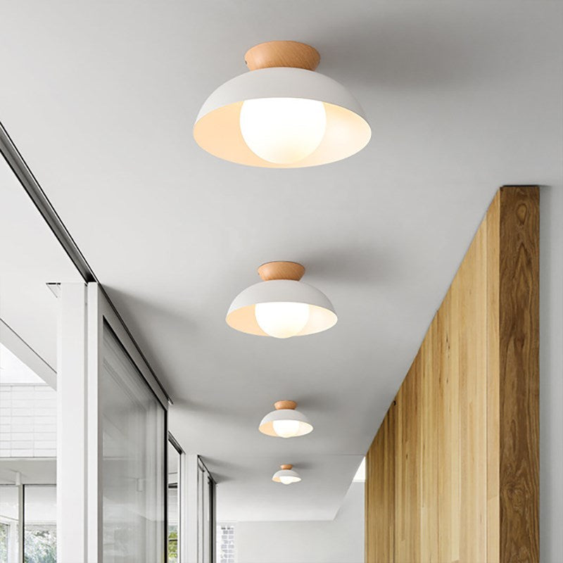 Four separately mounted White dome ceiling lights with wood accents along a corridor