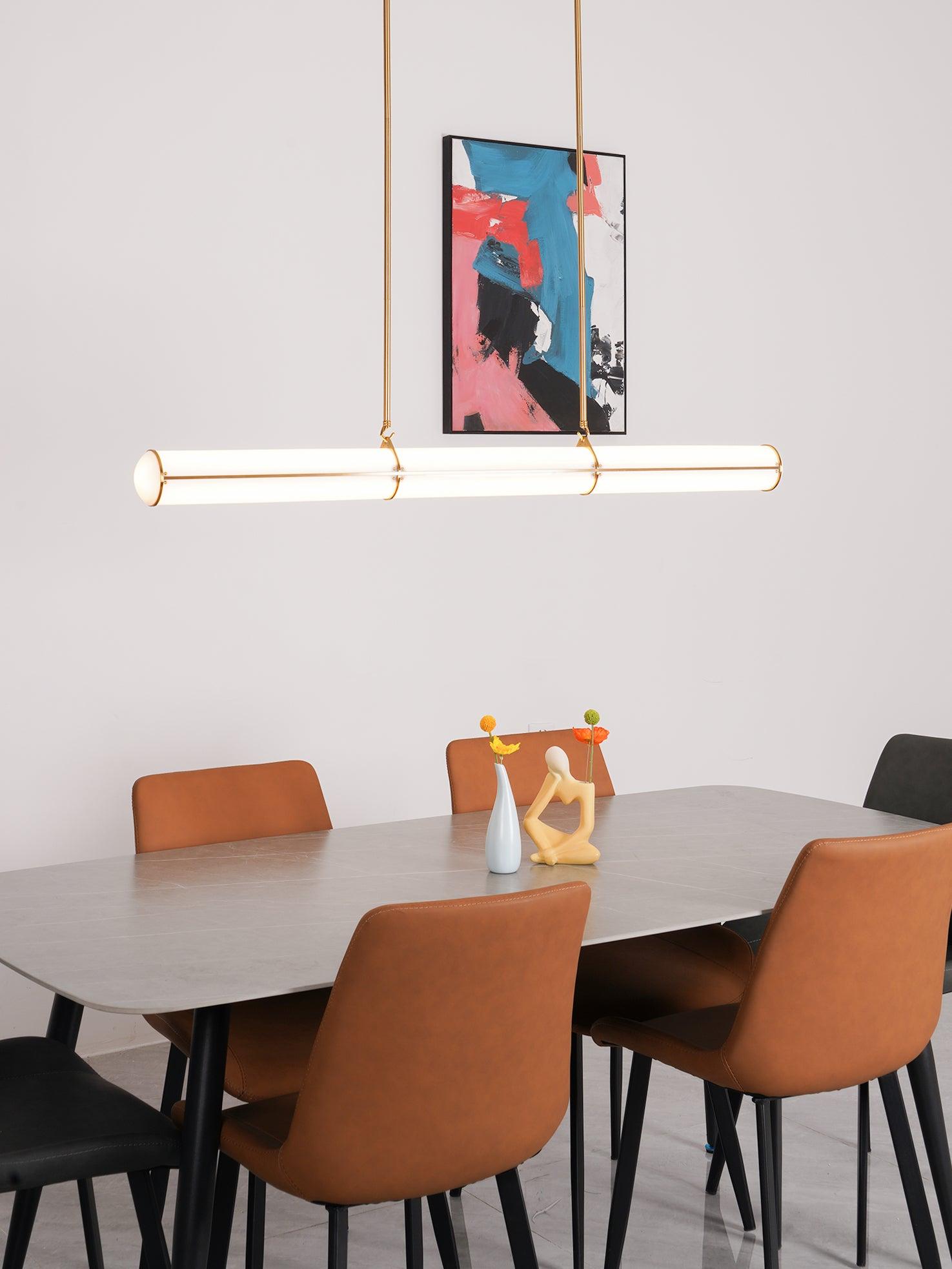 Straight cylindrical pendant above orange dining chairs