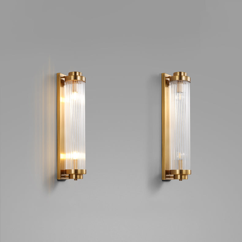 Two Gold glass-rod wall lights on a grey wall, with the left fixture illuminated and the right fixture unlit