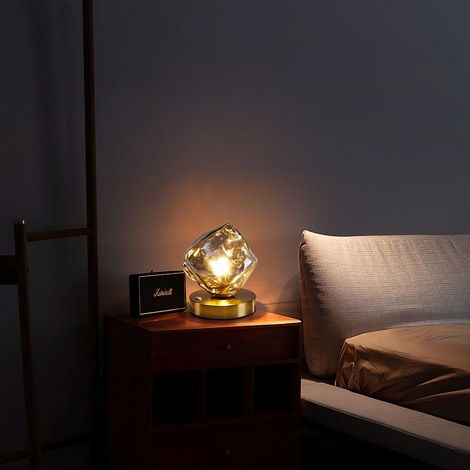 Ice Stone gallery lamp with a round gold-tone base beside a black speaker on a dark wood bedside unit