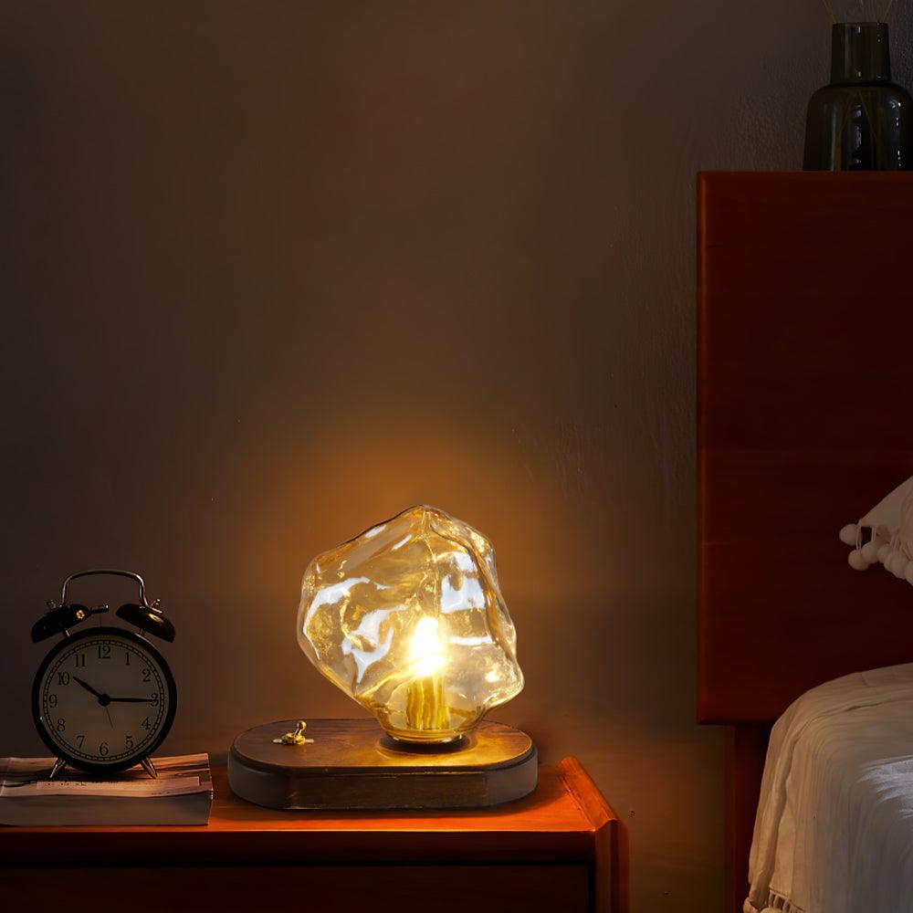 Glowing Ice Stone lamp beside a black alarm clock on books in a darker bedroom scene