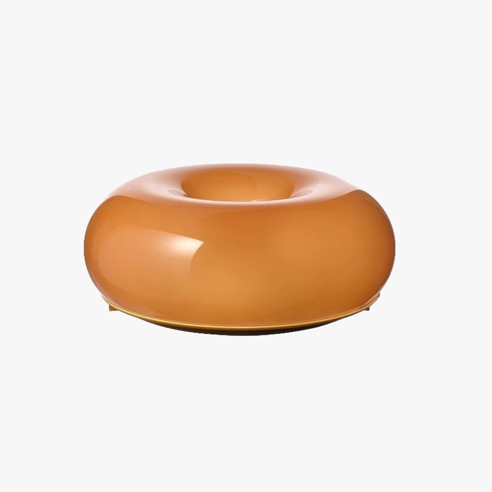 Orange donut-shaped lamp with a glossy rounded body and thin gold-tone lower rim against a plain white background